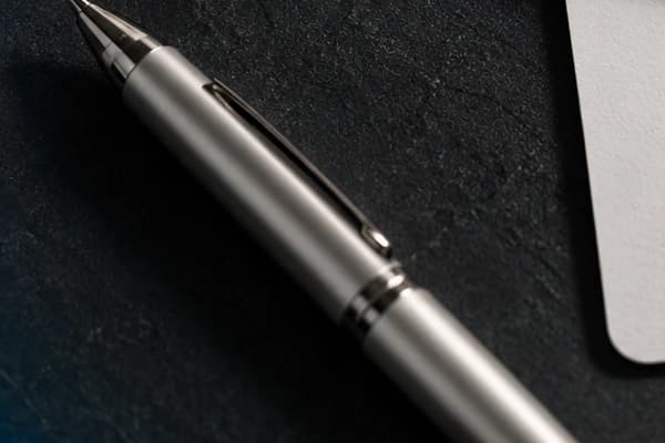 Stylo posé sur un bureau sombre — rédaction éditoriale